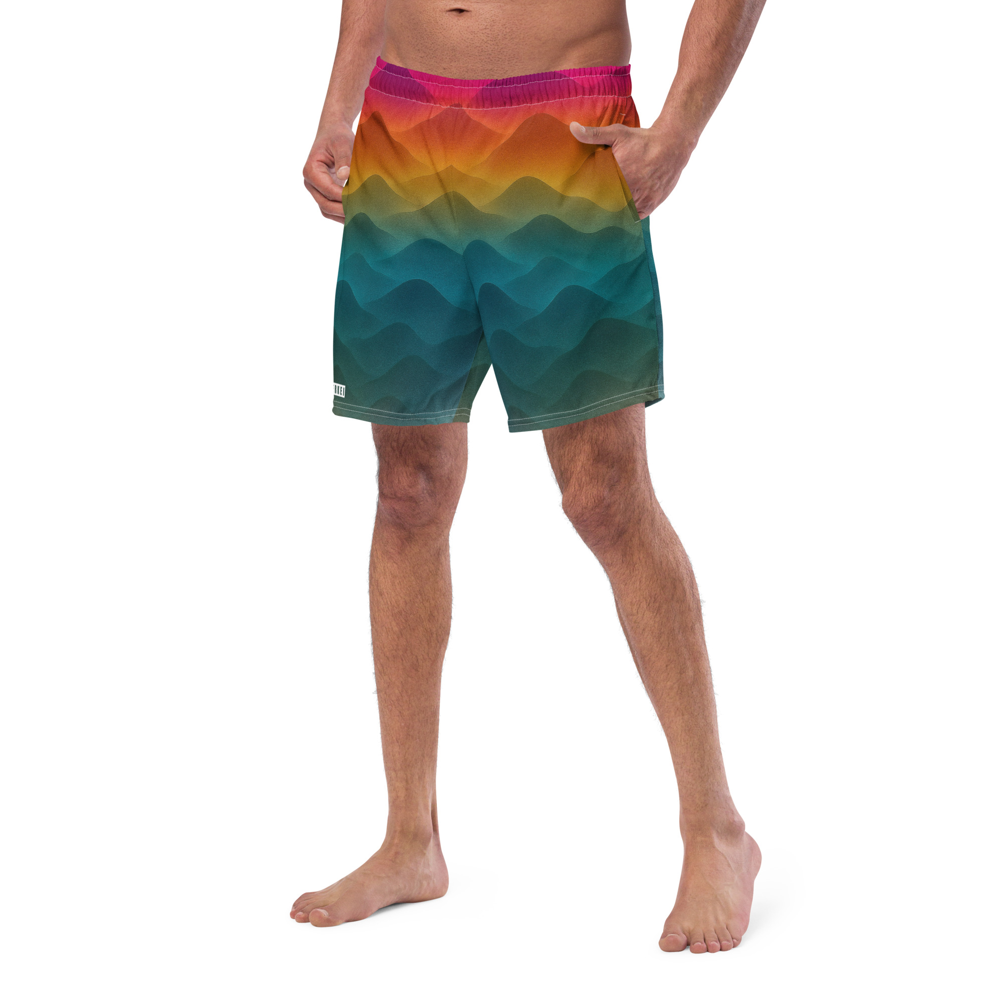 Mann trägt farbenfrohe BERKEI Badehose Forest Sunrise mit wellenförmigem Design