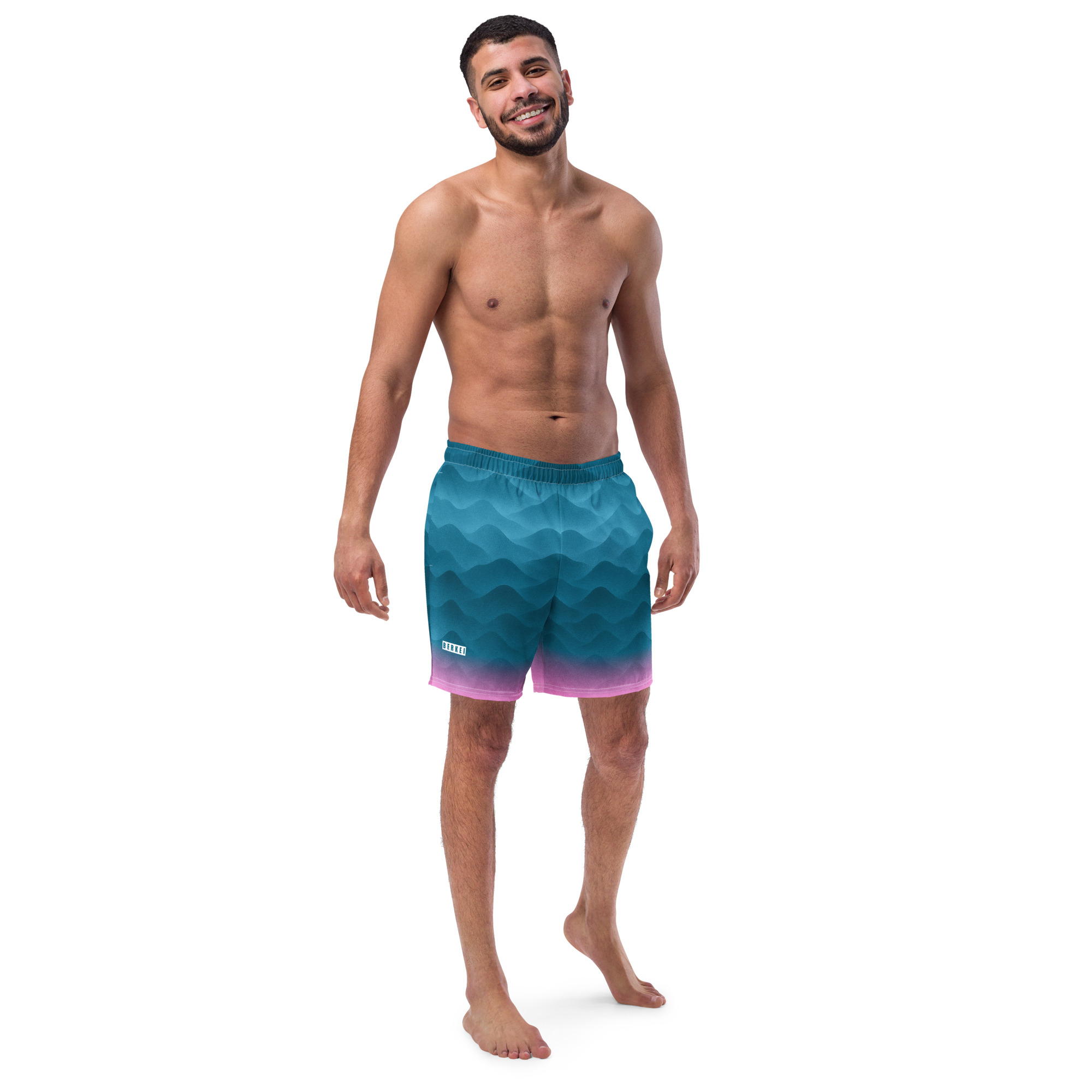 Mann trägt BERKEI Badehose Fountain Blue mit Wellenmuster am Strand