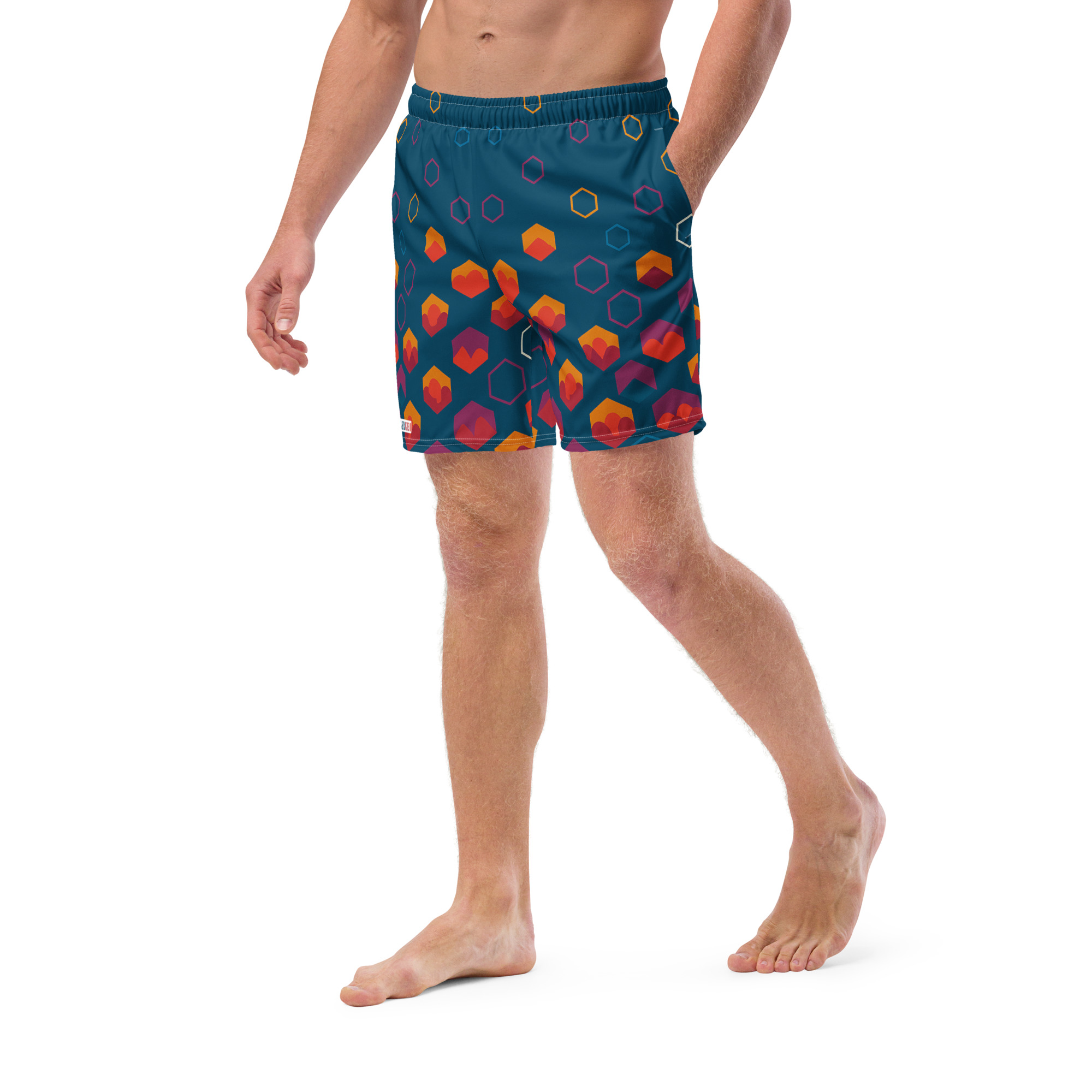 Mann trägt BERKEI Badehose Night Gear mit buntem geometrischem Muster am Strand