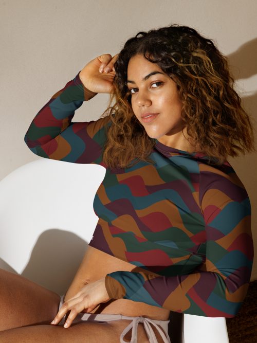 Junge Frau trägt das BERKEI Recycelte Langarm Crop Top Indian Summer mit buntem Wellenmuster.