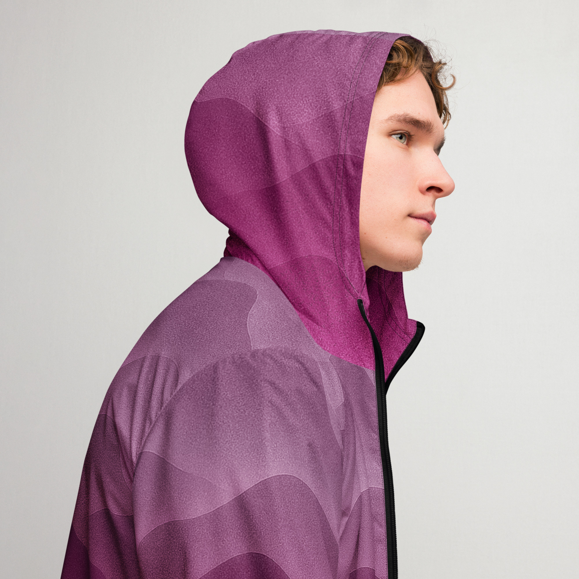 Junger Mann trägt den BERKEI Windbreaker Hazy Purple mit Kapuze, stilvolles Design inViolett-Tönen.