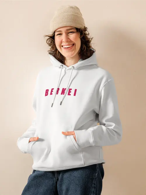 Junge Frau trägt gemütlichen BERKEI Hoodie Bio Vegan in Weiß mit beerenfarbenem Schriftzug.
