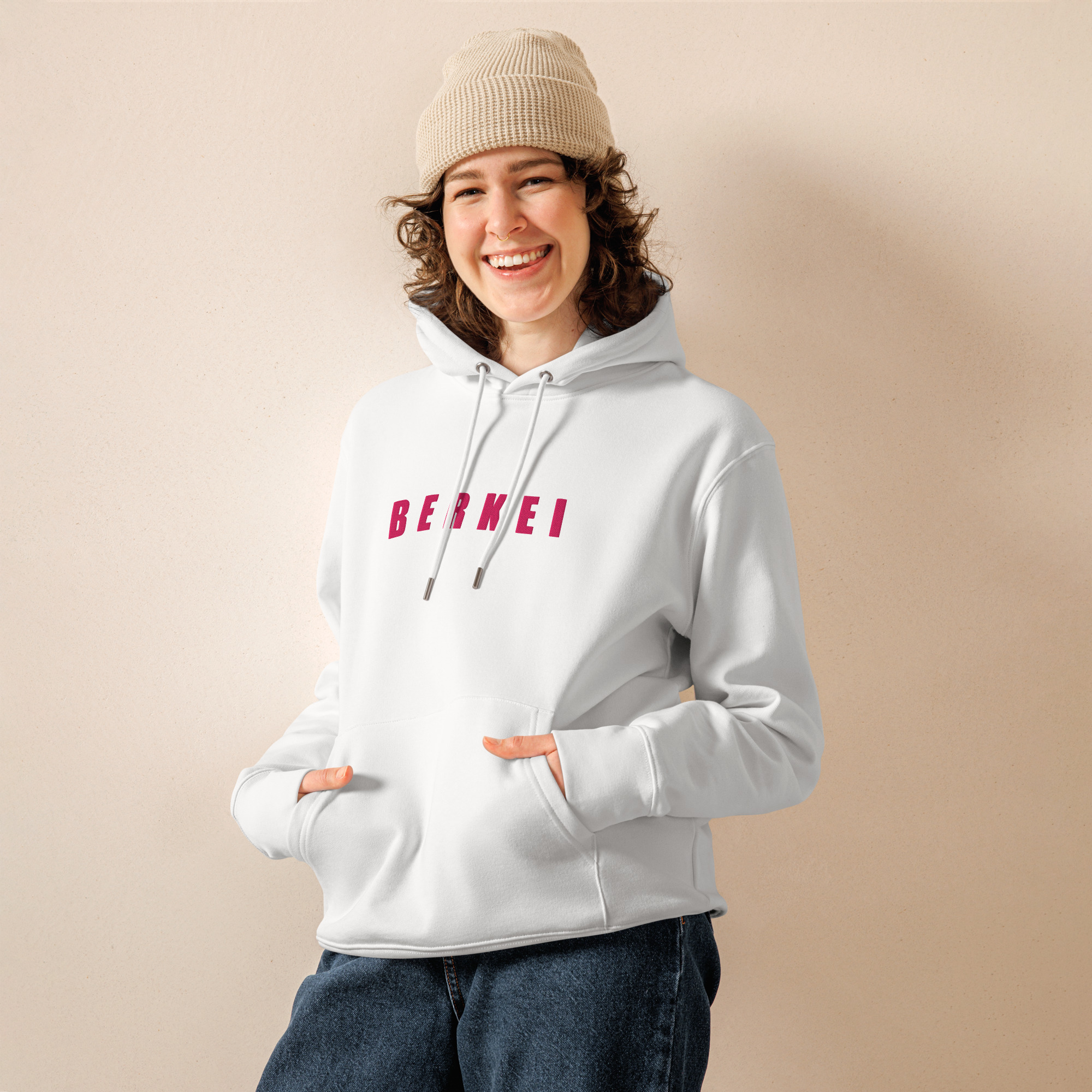 Junge Frau trägt gemütlichen BERKEI Hoodie Bio Vegan in Weiß mit beerenfarbenem Schriftzug.