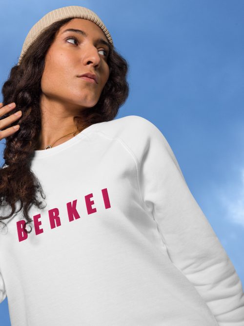 Frau trägt weißen BERKEI Unisex Bio Pullover vor wolkigem Himmel
