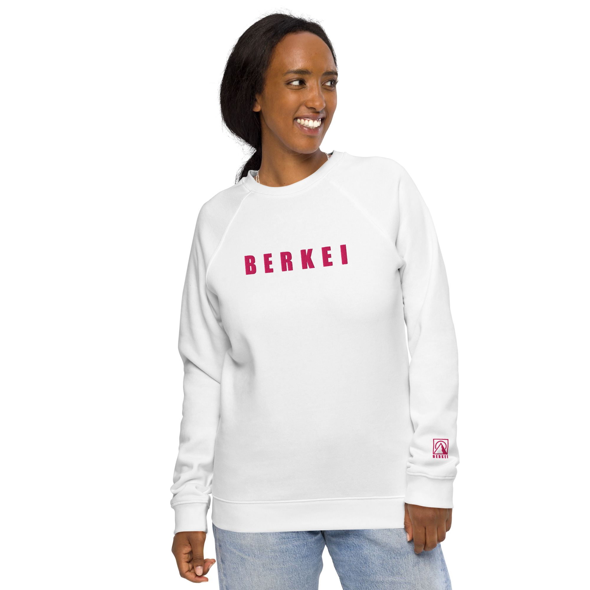 Weißer BERKEI Unisex Bio Pullover mit pinkem Schriftzug, bequem getragen von einer lachenden Frau.