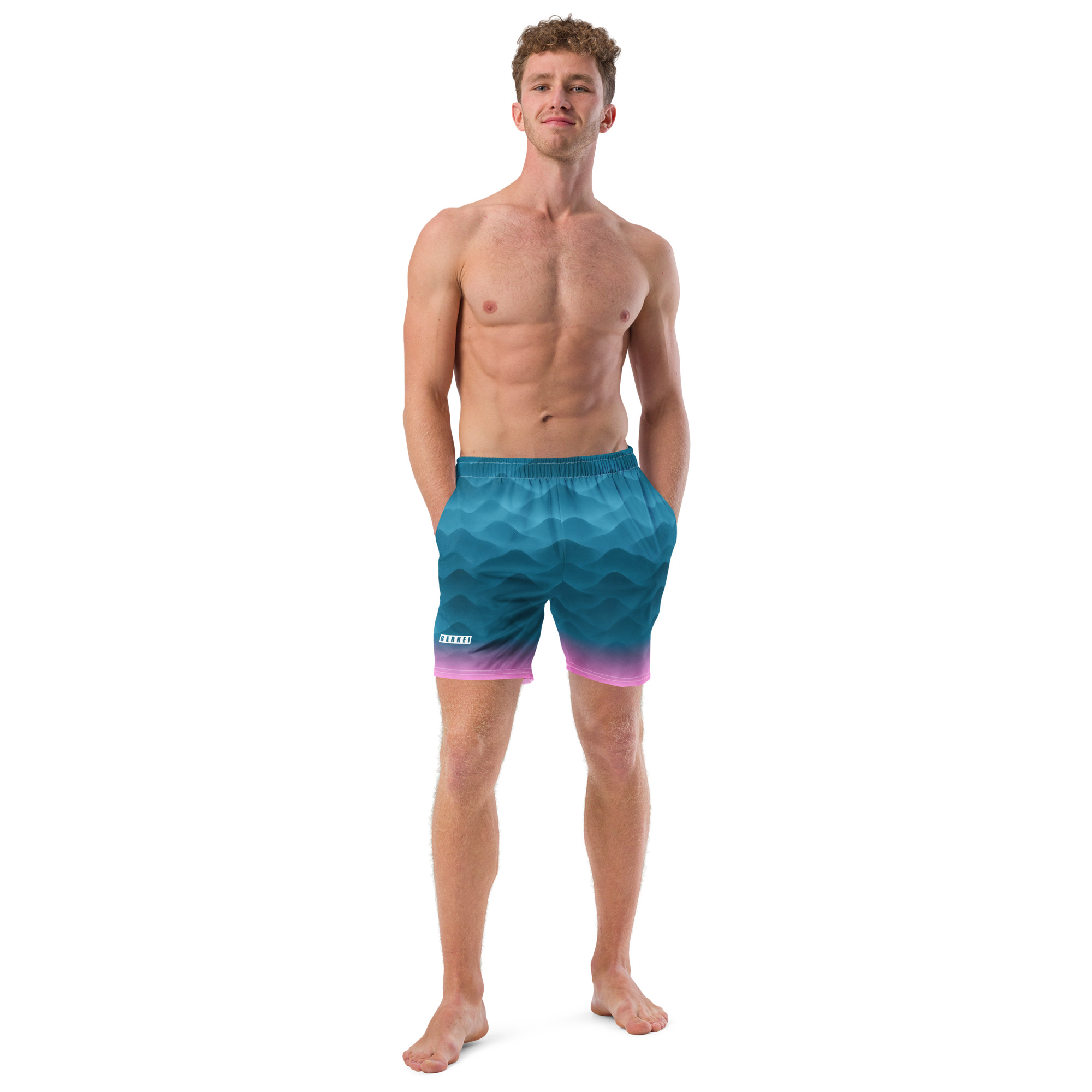 Mann trägt BERKEI Badehose Fountain Blue mit wellenförmigem Design am Strand