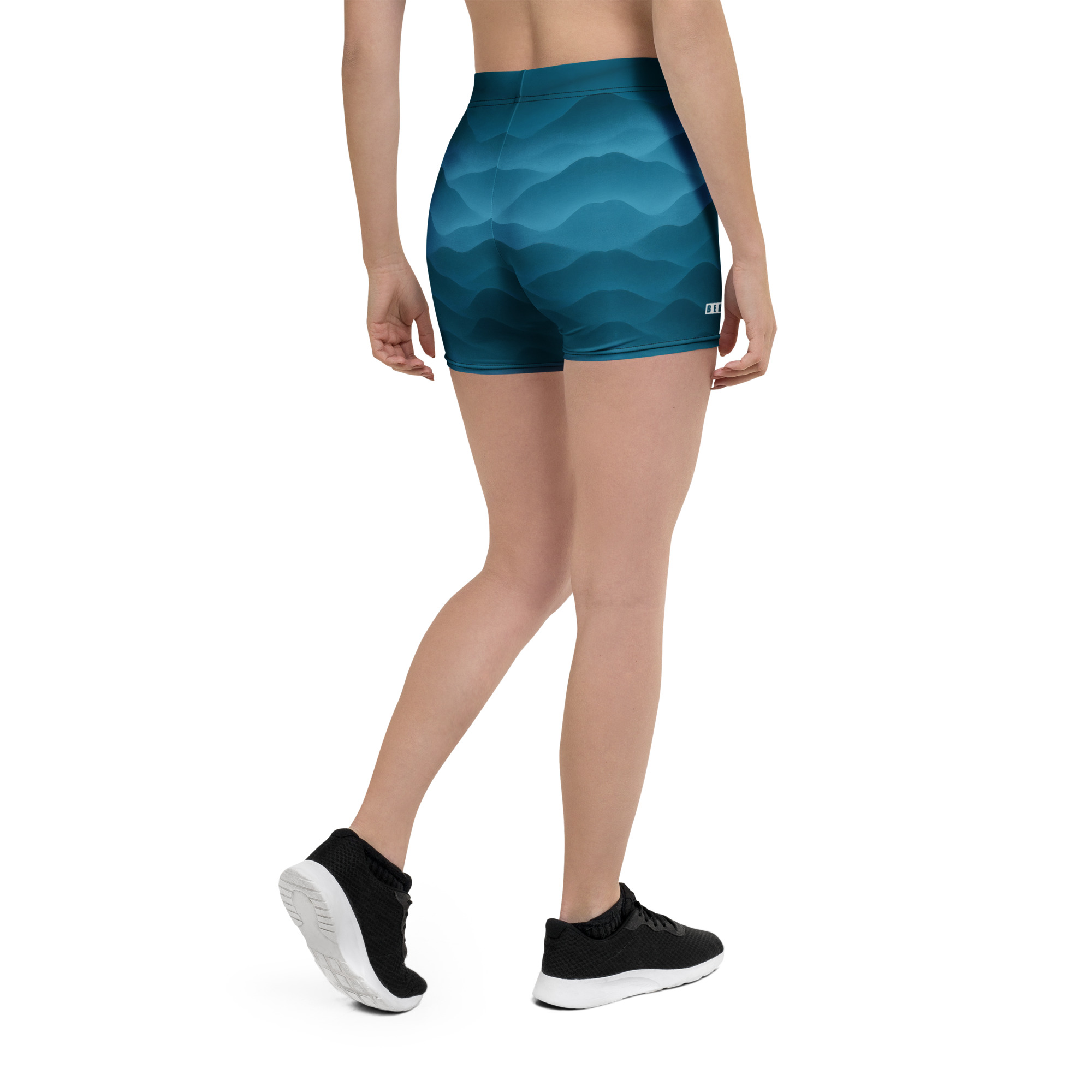 Frau trägt sportliche BERKEI Shorts in Fountain Blue mit attraktivem Wellendesign.