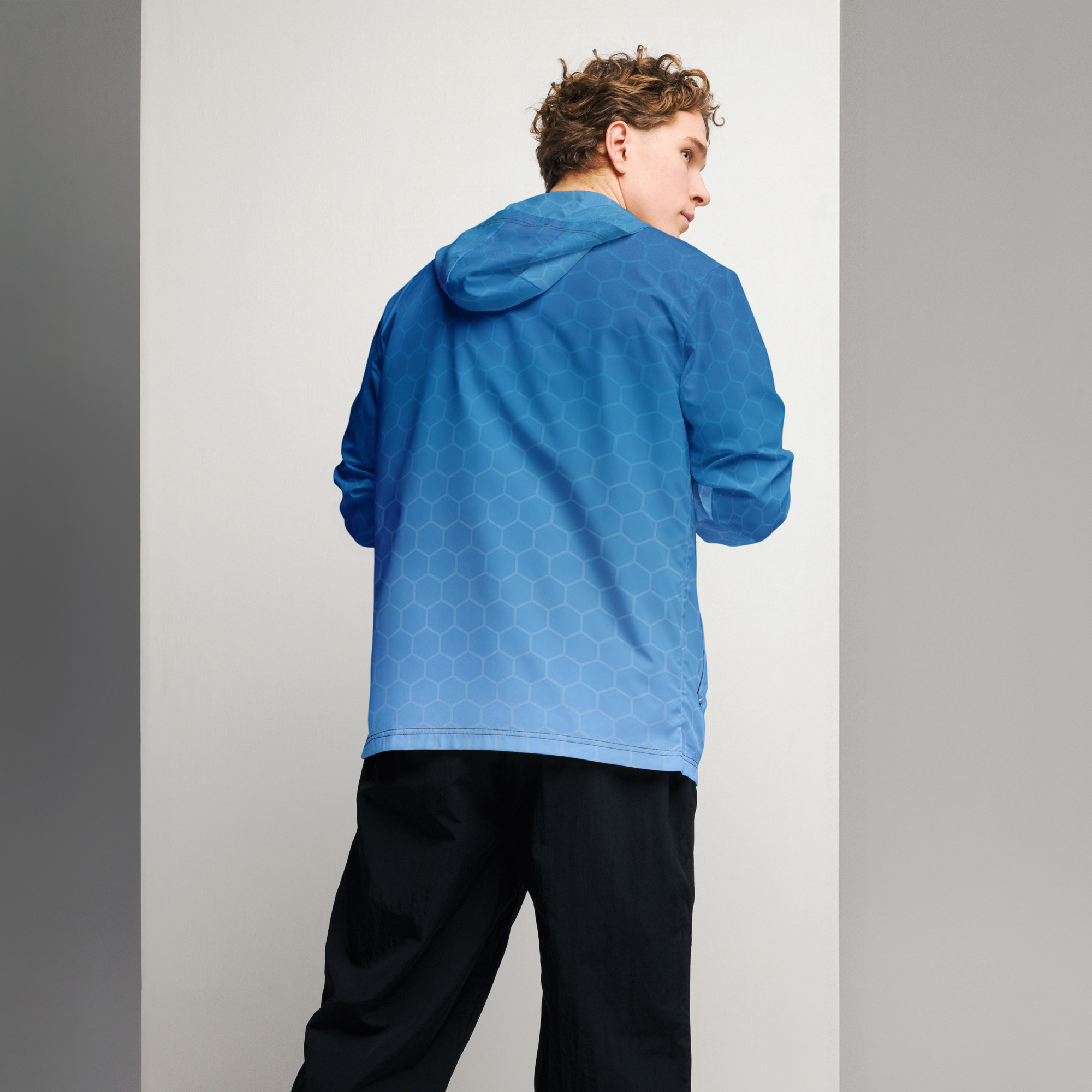 Junger Mann trägt leichten BERKEI Windbreaker in blau von hinten.