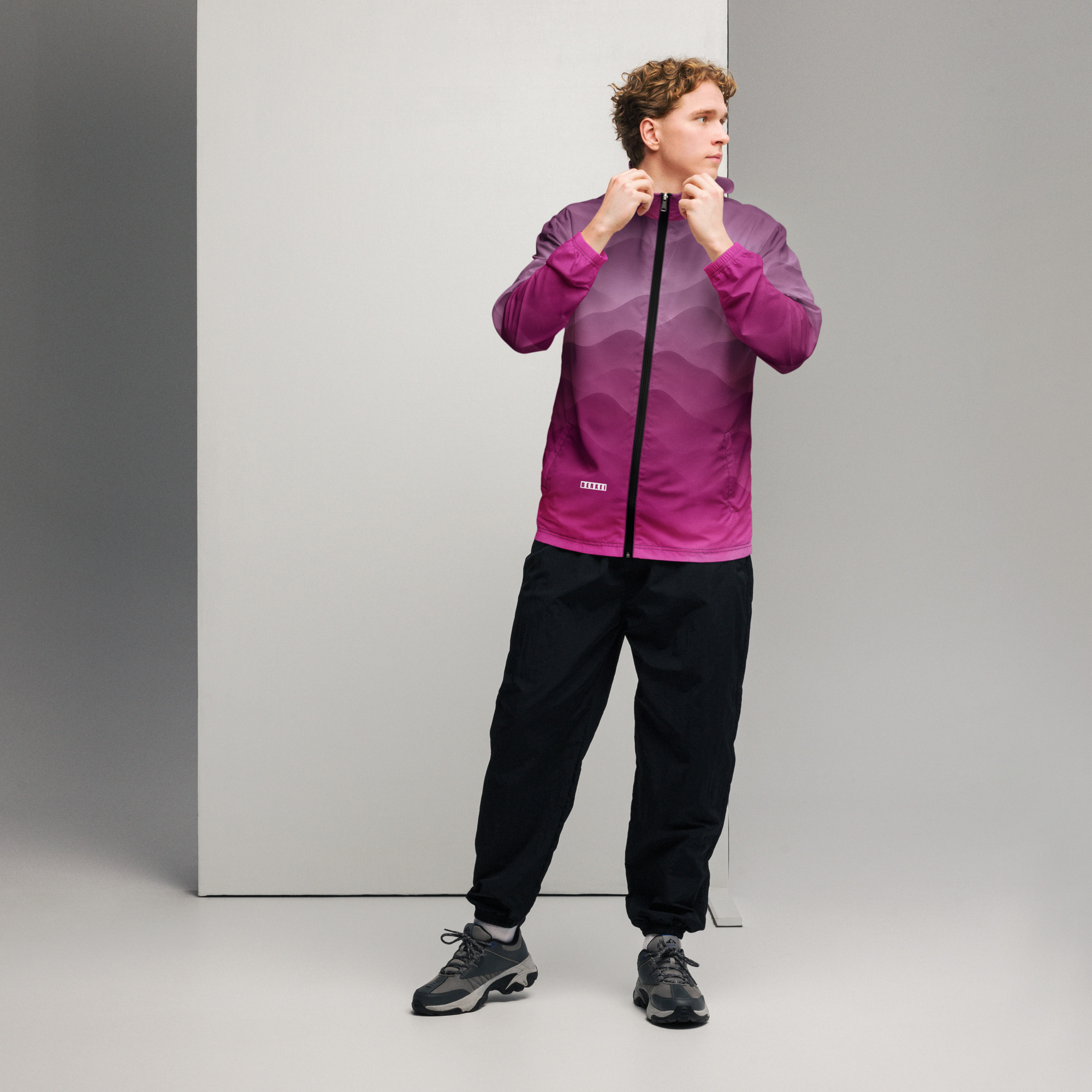 Mann trägt BERKEI Windbreaker Hazy Purple mit Farbverlauf vor neutralem Hintergrund