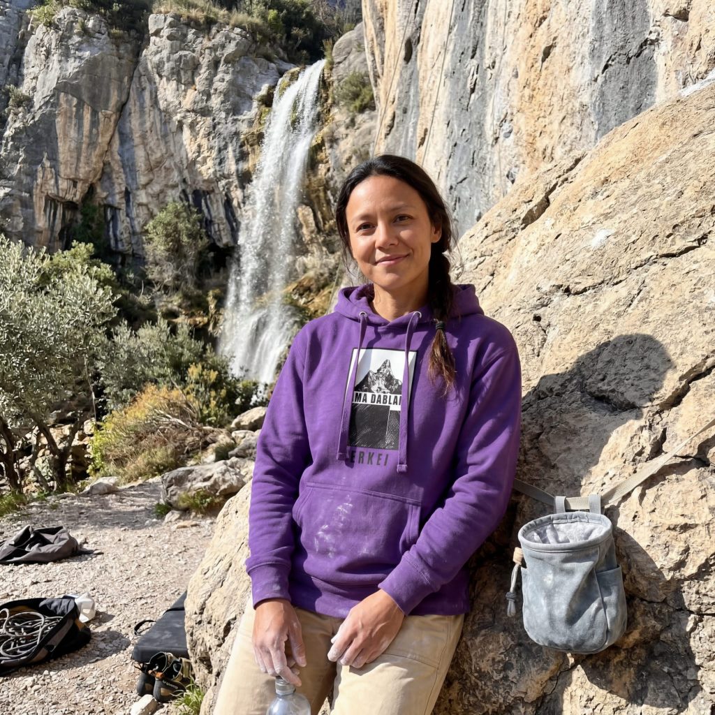 Frau trägt lila BERKEI Ama Dablam Hoodie bei Outdoor-Aktivität vor Wasserfall