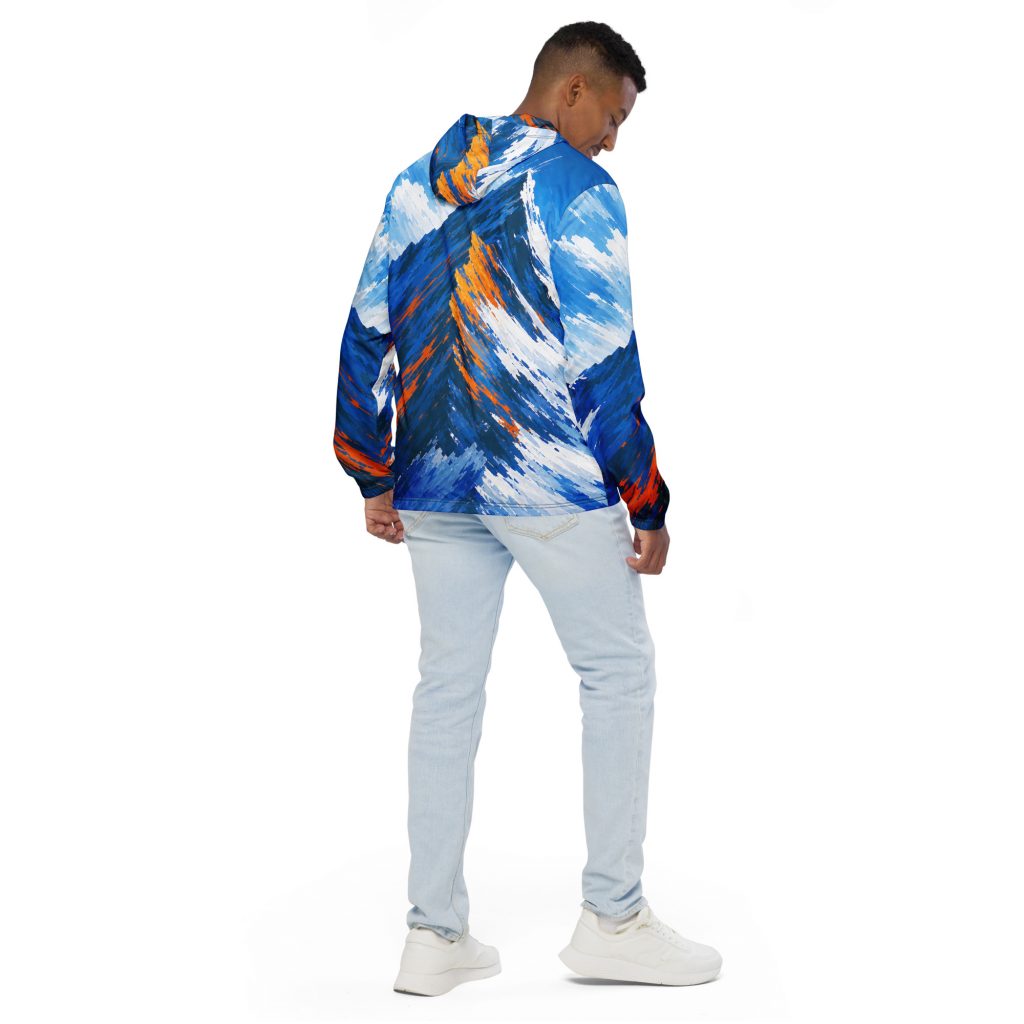 Junger Mann trägt bunten BERKEI Windbreaker Unisex Alpine Rush mit Bergmuster.